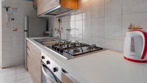 Uma cozinha moderna com fogão a gás, pia e chaleira vermelha.