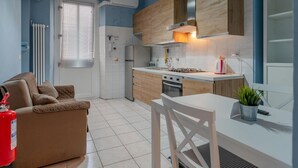 Uma cozinha compacta com área de refeições, um sofá e um extintor de incêndio.