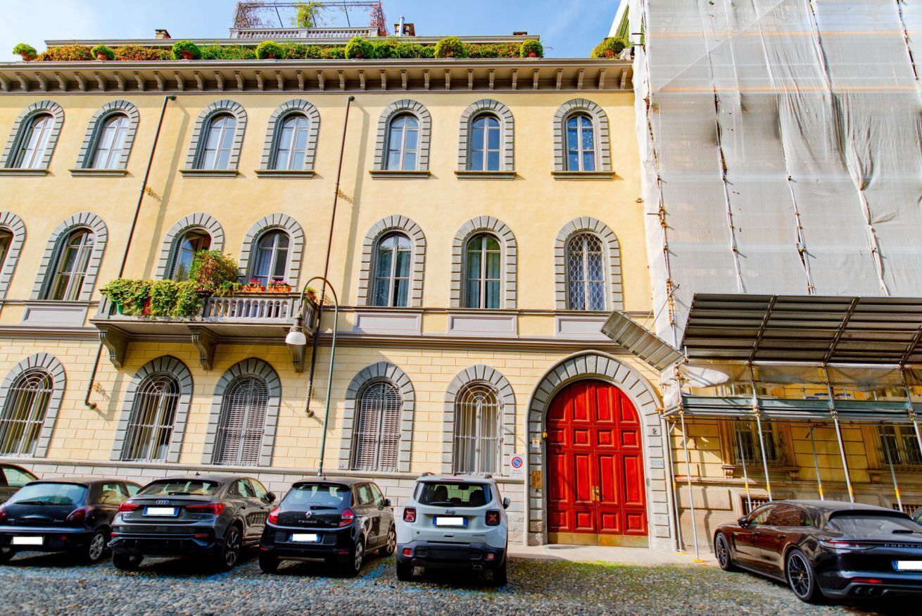 Un edificio con puerta roja, varias ventanas y coches estacionados adelante.