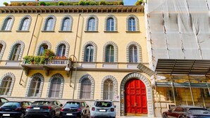 A building with a red door, multiple windows, and parked cars in front. - [Centro, elegante]: The Queen by HappyHosTorino* (Torino)