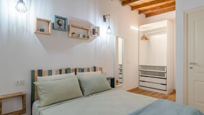 Ein Schlafzimmer mit einem Bett, einem Holzkopfende, Nachttischen, einem Kleiderschrank und einem Spiegel.