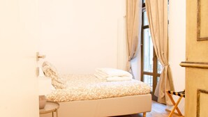 A bedroom with a bed, a small table, and a window with curtains. - Toffee House by HappyHosTorino (Torino)