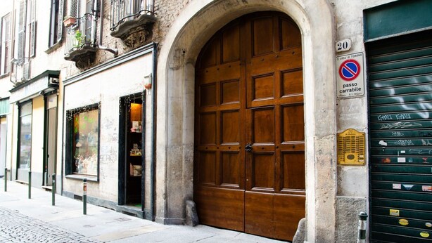 A large wooden door with a stone archway, a no parking sign, and a metal gate on a cobblestone street. - Toffee House by HappyHosTorino (Torino)