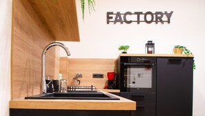 A modern kitchen with a wooden countertop, a sink, a black refrigerator, and a wall-mounted sign that reads "FACTORY". - Toffee House by HappyHosTorino (Torino)