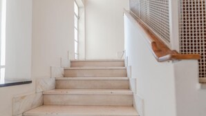 Una escalera con barandilla de madera y protección metálica.
