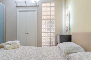 Un dormitorio con cama, armario, ventana con vistas y mesita de noche.