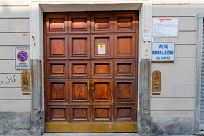 Una gran puerta de madera con umbral metálico, un letrero de no estacionamiento y una señal que indica un taller de reparación de automóviles.