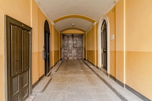 Un pasillo con suelo de baldosas, dos puertas a cada lado y un gran portal de madera al final.