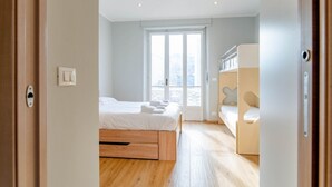 Een moderne slaapkamer met een groot raam, een bed, een inbouwbank en een garderobe.