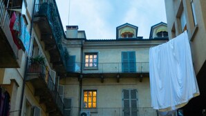 A narrow street with multi-story buildings, balconies, and laundry hanging. - La Terrazza sui Tetti (Torino)