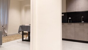 A modern kitchen with grey cabinets, a black countertop, and a small table with a tablecloth. - La Terrazza sui Tetti (Torino)