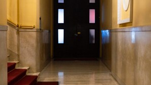A marble-floored hallway with red carpeted steps leading to a dark door with illuminated panels. - [AC, Centralissimo] Bertola by HappyHosTorino (Torino)