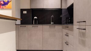 A modern kitchen with light wood cabinets, a black countertop, and stainless steel appliances. - [AC, Centralissimo] Bertola by HappyHosTorino (Torino)