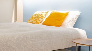 A bed with a white textured bedspread and two pillows, one with a yellow pattern and one solid yellow. - [AC, Centralissimo] Bertola by HappyHosTorino (Torino)