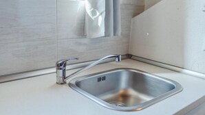 Et moderne køkken med en stålvask, en kromarmatur og en lys bordplade.