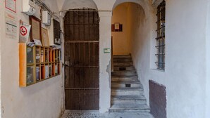 A narrow hallway with a wooden door, a staircase, and a row of glass display cases on the left. - Casa M&M] Luminosa: Borgo Dora (Torino)