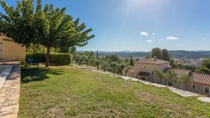 A residential area with a pool, stone pathway, and a view of distant hills.