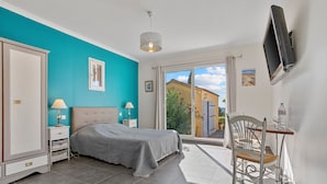 A bedroom with a bed, bedside tables, a TV, a chair, and a view of the outside.