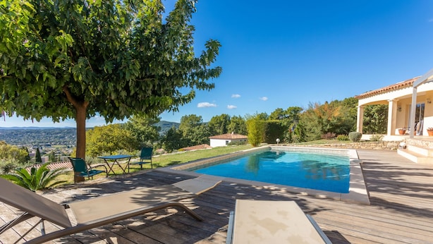 A wooden deck with lounge chairs, a swimming pool, and a view of the landscape.
