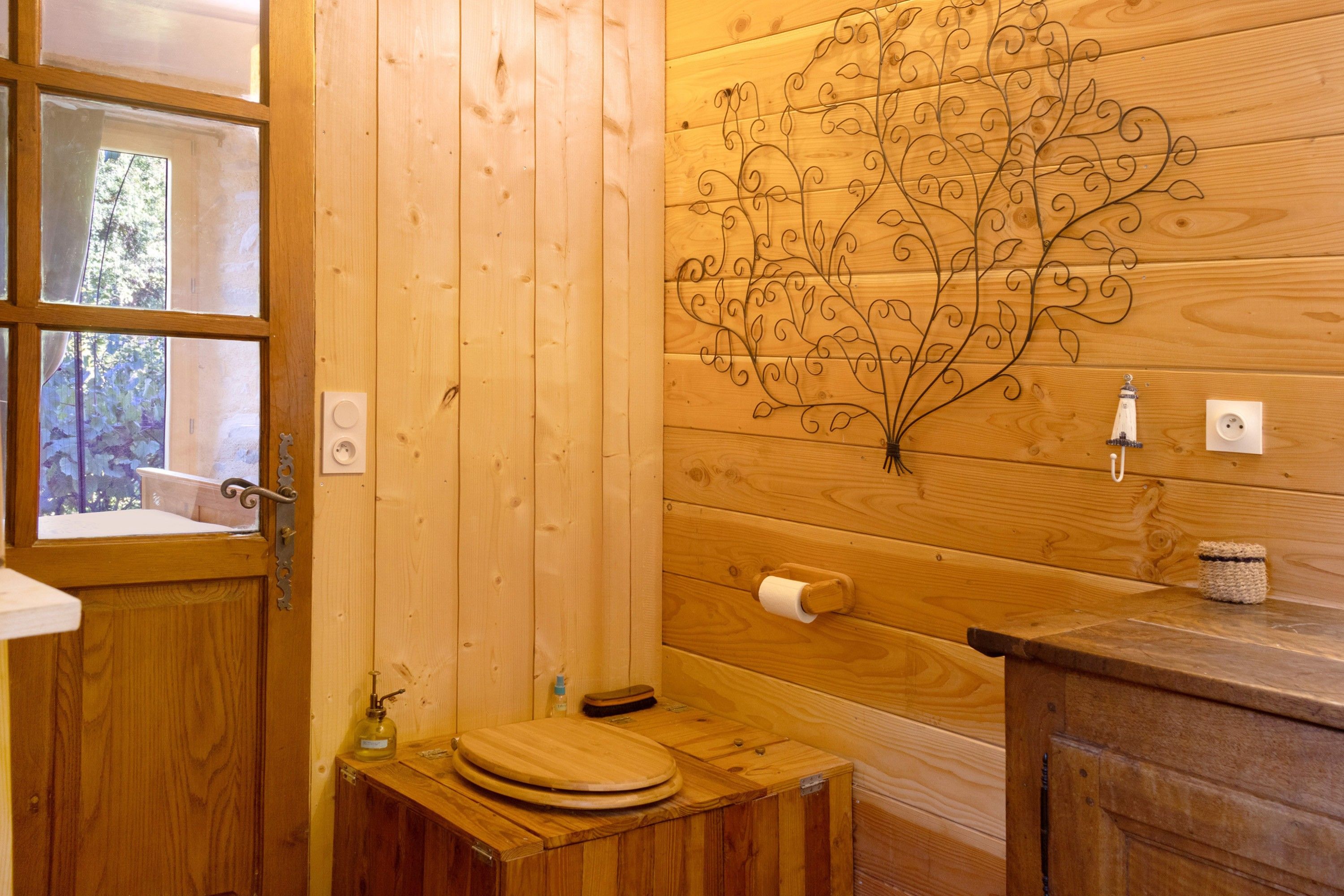 Une salle de bain en bois avec des toilettes, un lavabo et une fenêtre.