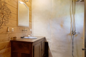 Un baño de madera con lavamanos, espejo y ducha.