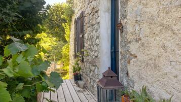 Un bâtiment en pierre doté d’une terrasse en bois, d’une lanterne et de plantes en pot.
