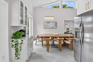 Een moderne keuken met een groot schiereiland, roestvrijstalen apparatuur en een eethoek met houten stoelen.