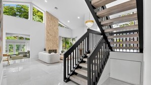 A modern interior with a staircase, a living area with sofas, and large windows. - Gorgeous Modern Beach Heated Pool House Sleeps 8 Central (Delray Beach)
