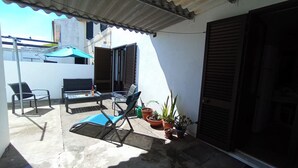 A small patio with a table, two chairs, a blue lounge chair, and potted plants. - Casa da Fatima in Angra do Heroismo (Angra do Heroismo)