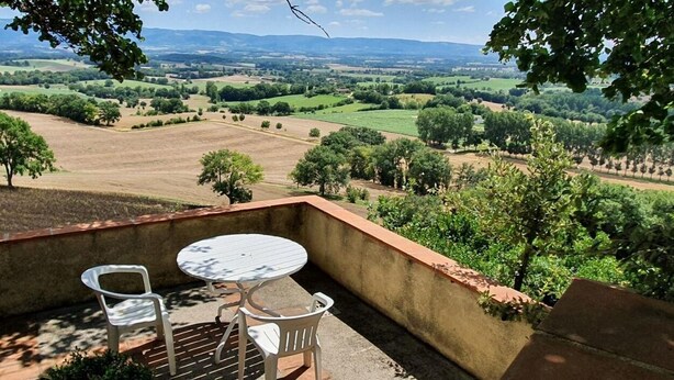 Eine Terrasse mit Tisch und Stühlen mit Blick auf eine ländliche Landschaft.