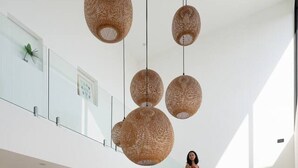 A modern kitchen with a pink countertop, wooden stools, and hanging wicker light fixtures. - Palmaya Villa - Piscine & Vue mer - 3 chambres (Ko Samui)