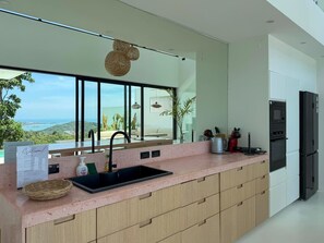 A modern kitchen with a large window, a sink, and a refrigerator.