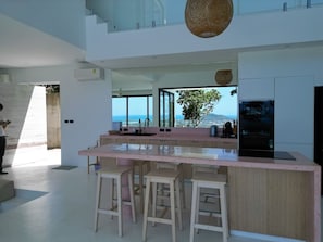 Una cocina moderna con una isla grande, taburetes de bar y vistas al océano.