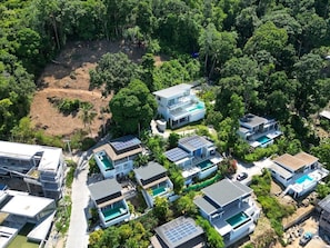 An aerial view of a residential area with modern houses, solar panels, and swimming pools.