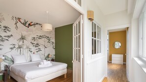 Een slaapkamer met een bed, een muurschildering, een deur en een gang.