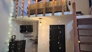 Habitación estilo loft con escalera de madera, un televisor en la parte superior y una mesa con letras iluminadas que dicen 'TEAM'.