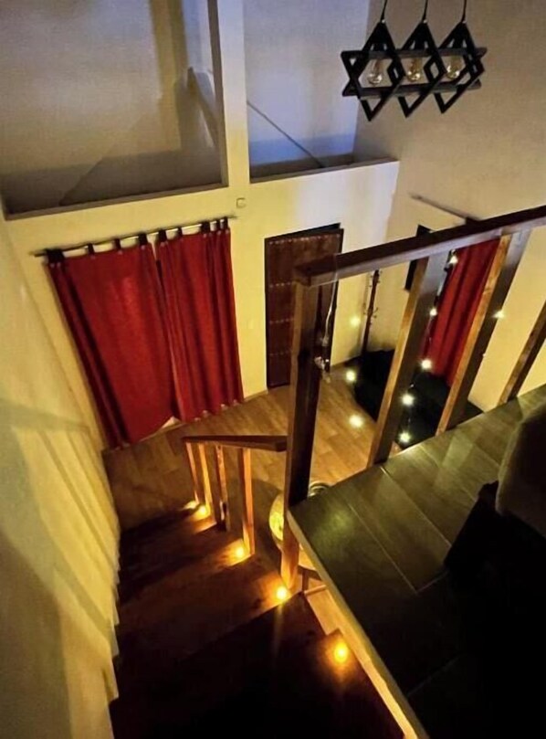 A staircase with wooden railings and red curtains, leading to a lower level.