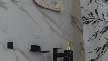Ein Badezimmer mit Marmorwand, einem Spiegel, einem Waschbecken, einer Duschvorhang und einem Handtuchhalter.