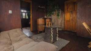 A rustic room with a sofa, wooden barrels, a round table, and a wooden door.