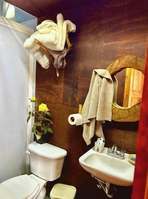 A bathroom with a toilet, sink, and a wooden wall. - Trini Tree House — Nido By GEstores (Omitlán de Juárez)
