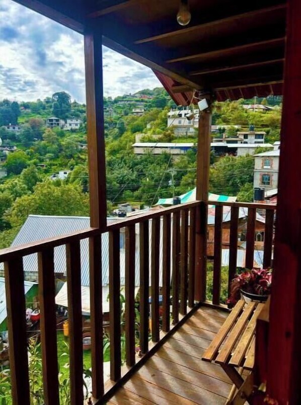 A wooden balcony with a view of a green hillside and buildings. - Trini Tree House — Nido By GEstores (Omitlán de Juárez)