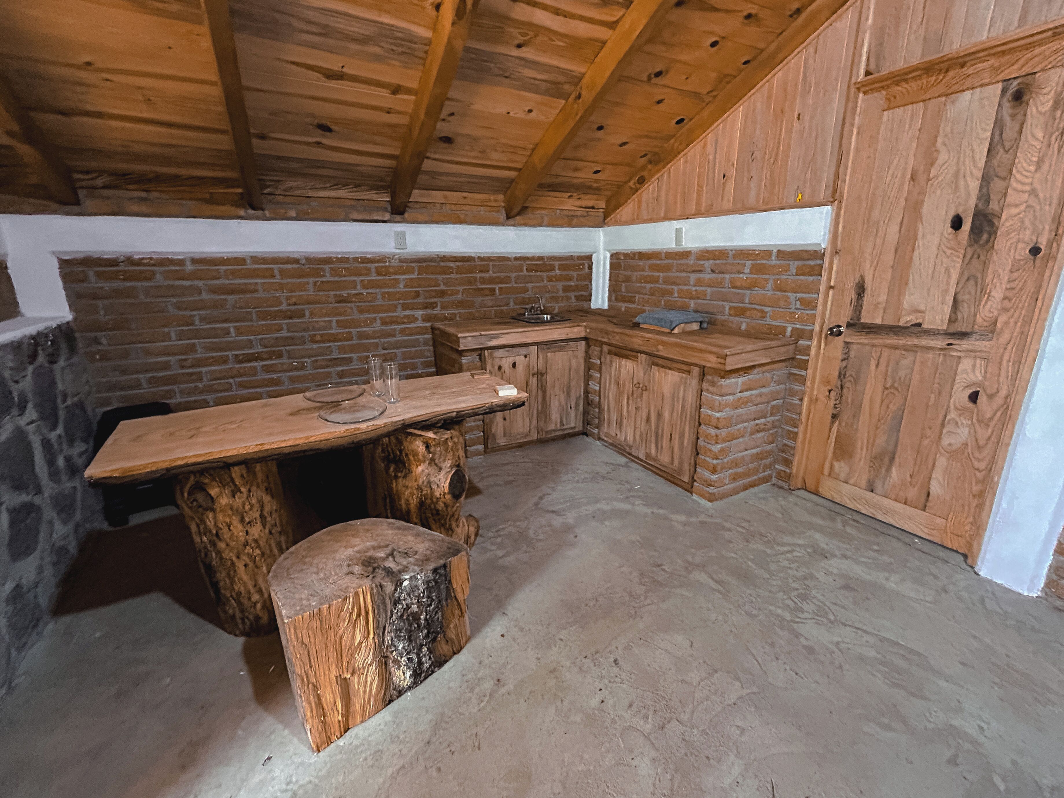 Une cuisine rustique avec une table en bois, des murs en briques et un mur en pierre.