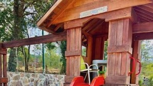 Una estructura de juego de madera con un tobogán rojo y una mesa de picnic.