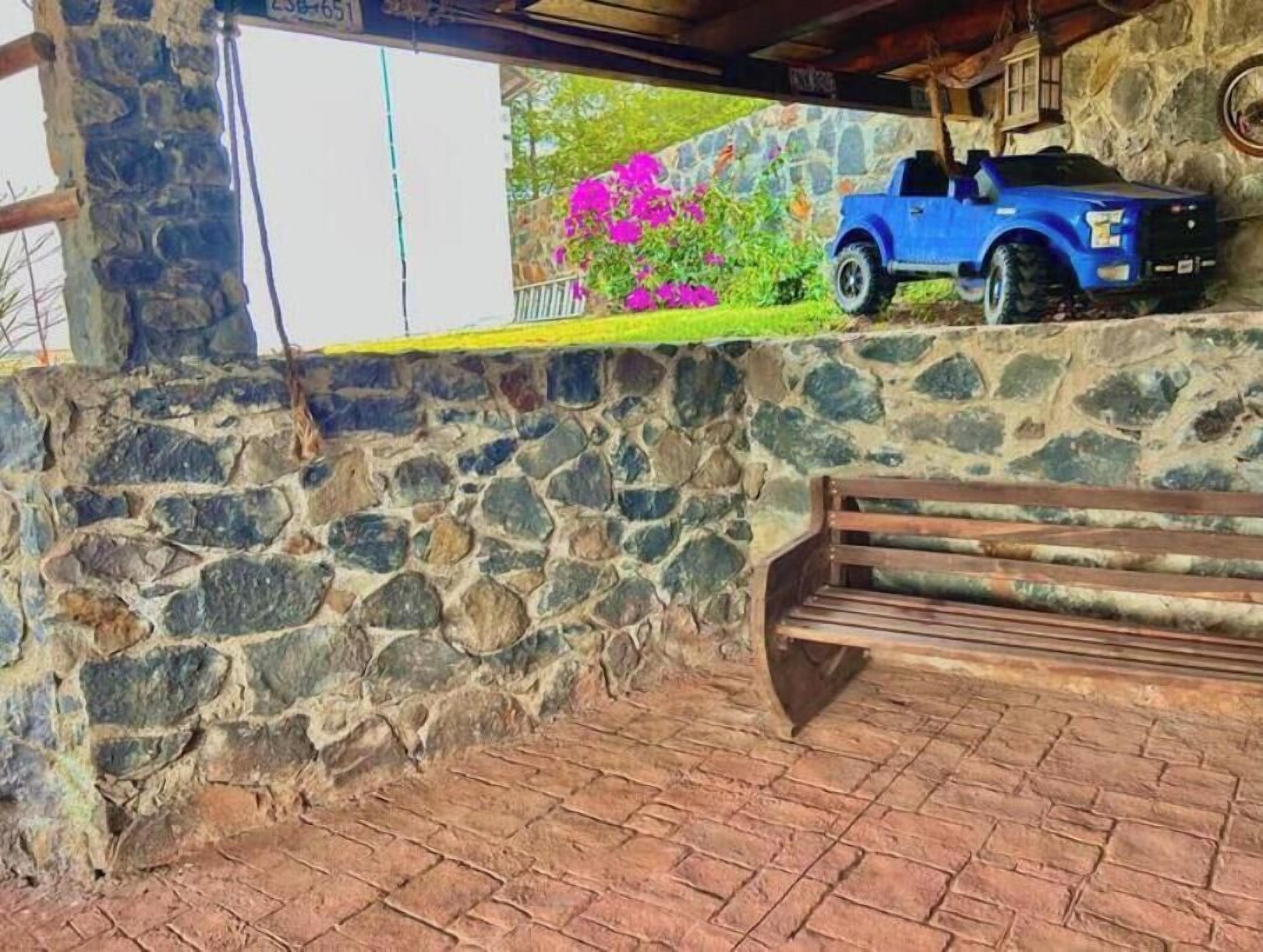 Un mur de pierres avec un banc et un camion bleu garé à l’extérieur.