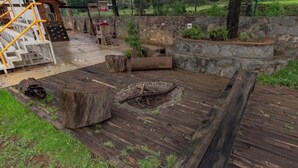 A wooden deck with a fire pit, stone walls, and a playground area.