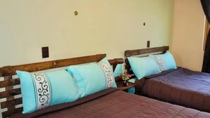 Une chambre avec deux lits, chacun doté d’une tête de lit en bois et d’une couvre-lit marron.