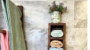Une salle de bain équipée d’un porte-serviettes où sont rangées plusieurs serviettes et d’une étagère en bois sur laquelle sont pliées d’autres serviettes.