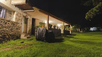 Un bâtiment en pierre doté d’un patio couvert, de plantes en pot et d’une pelouse.