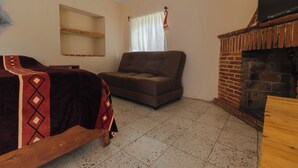 Ein Zimmer mit einer Couch, einem Holzbett, einem Kamin und einem Fernseher.