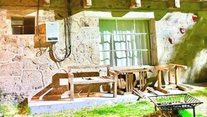 Un área de estar al aire libre de estilo rústico, con pared de piedra, mesa de madera y un banco.